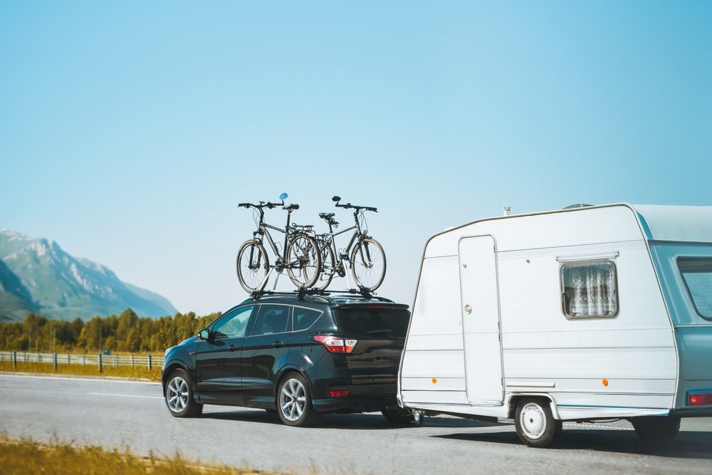 SUV car truck with bicycles on the roof and towing RV. Family road trip